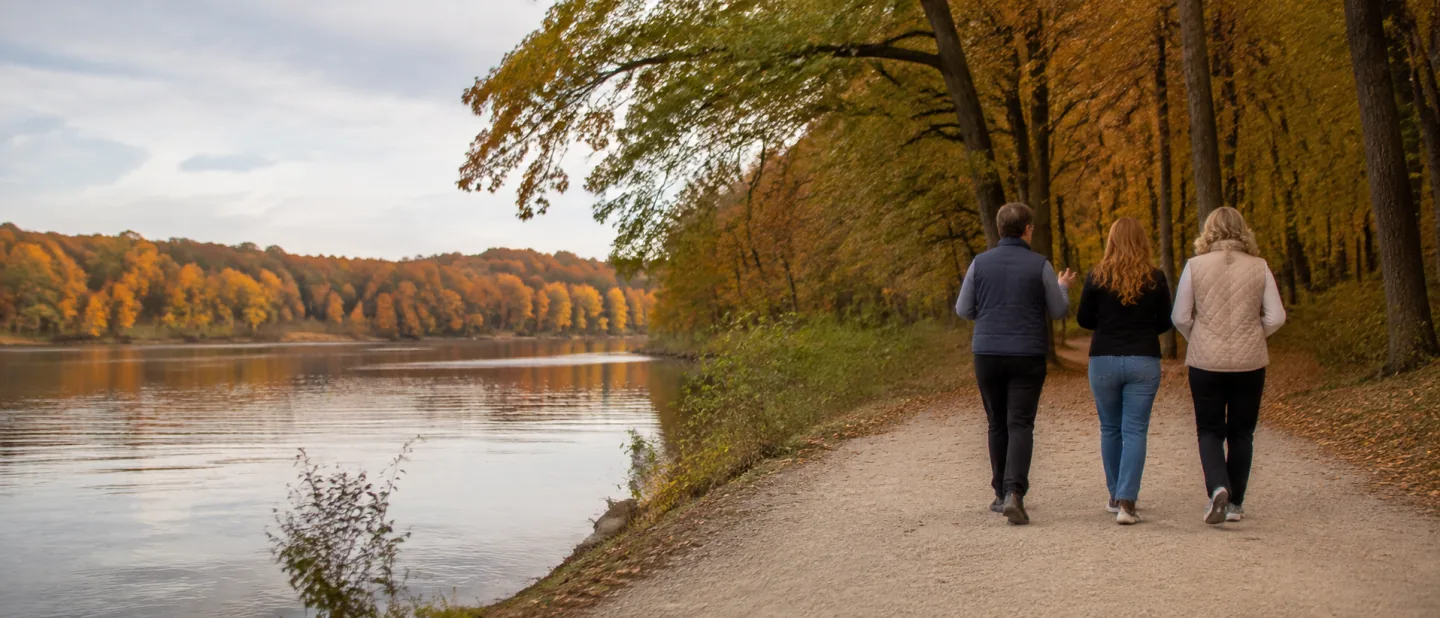 Samantha and two companions walking beside a lake beneath autumn trees